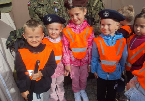 dzieci w kamizelkach odblaskowych stojące na tle młodych żołnierz