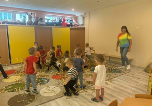 Dzieci łapiące serpentynę kobieta w kolorowej bluzce rzuca serpentyna
