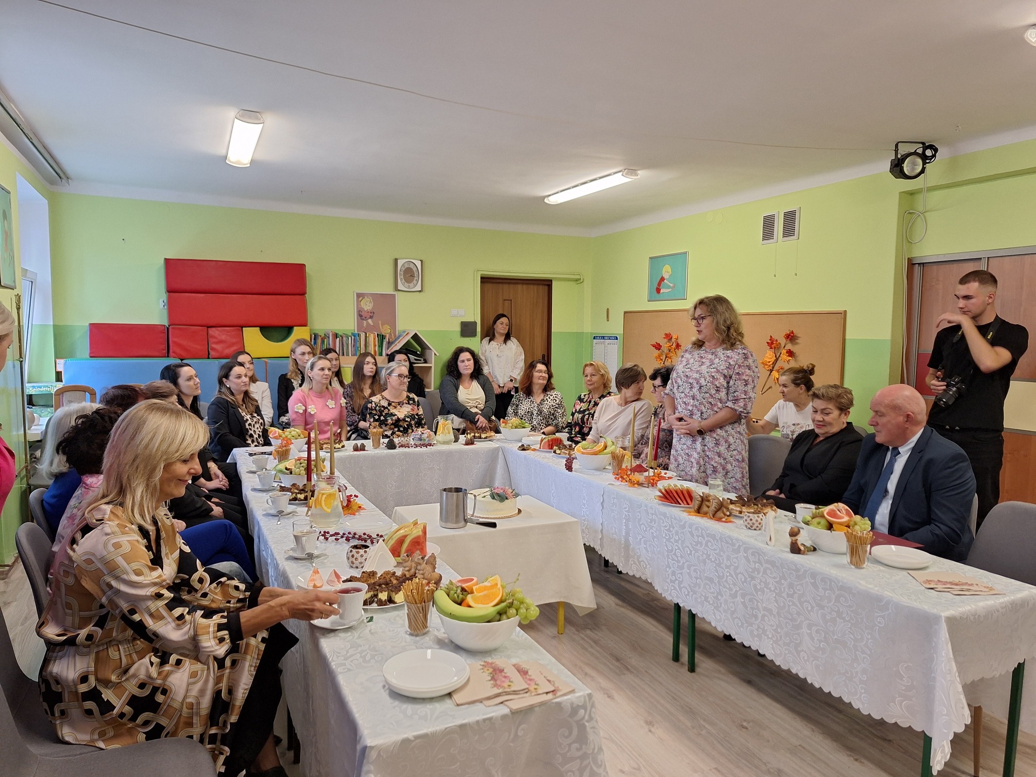 osoby dorosłe siedzące przy stole słuchające przemowy