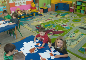Dzieci malują farbami szablon misia.