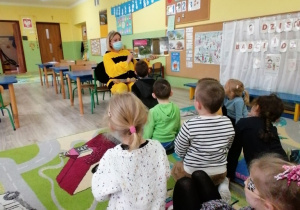Dzieci słuchają książki czytanej przez panią bibliotekarkę w przebraniu pszczółki.