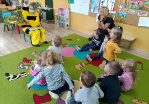 Dzieci słuchają bajki czytaną przez panią bibliotekarkę w przebraniu pszczółki.