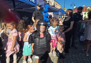 Dziecko w mundurze policyjnym, obronnym na tle grupy dzieci