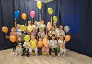 Grupa dzieci stojąca z kolorowymi balonami w dłoniach.