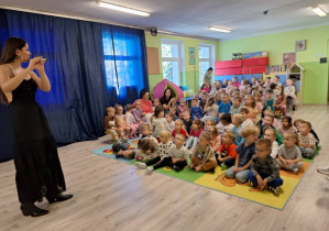 Kobieta grająca na flecie dla grupy dzieci.