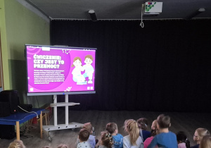 Ekran ilustrujący informacje o przemocy. Dzieci patrzące na duży ekran.