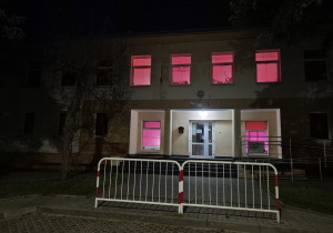 Budynek przedszkola z podświetlonymi na czerwono oknami.