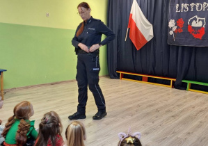 Pani policjantka stojąca na przeciwko grupy dzieci.