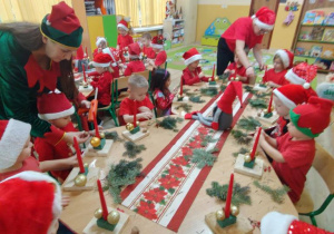 Dzieci siedzą przy stole i wykonują stroiki.