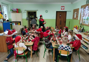 Dzieci siedzą przy stole i wykonują stroiki.