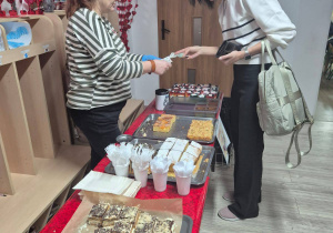 Kobieta kupująca ciasto podczas kiermaszu ciast w przedszkolu.