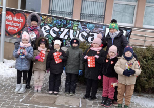 Dzieci stojące przed budynkiem Urzędu Miasta z puszkami WOŚP.