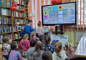 Grupa dzieci oglądająca prezentacje wyświetlaną na ekranie multimedialnym.