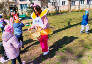 Dzieci szukające czekoladowych jajek na terenie ogrodu przedszkolnego.