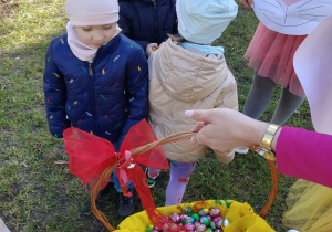 Dzieci wrzucające czekoladowe jajka do koszyczka. Koszyk pełen czekoladowych jajek.