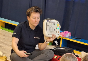 Pani pokazująca AEDtrainer.