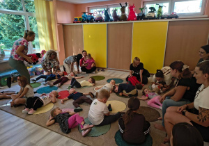 Dzieci oraz rodzice leżą na dywanie i słuchają muzyki