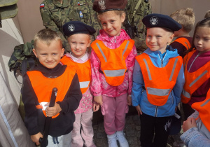 dzieci w kamizelkach odblaskowych stojące na tle młodych żołnierz