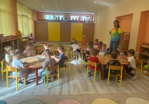 dzieci siedzące przy stoliku , kolorują obrazki