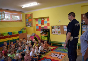 dzieci z grup słoneczka i motylki słuchają pana policjanta