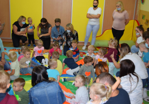 Dzieci z rodzicami siedzą na dywanie