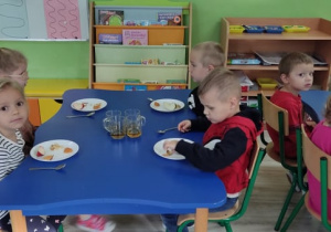 Dzieci przy stolikach próbują przetworów z jabłek.