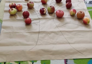 Dzieci przy stolikach próbują przetworów z jabłek.