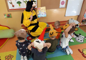 Dzieci słuchają opowiadania czytanego przez panią przebraną za pszczółkę.