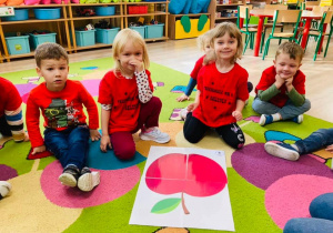 Dzieci układaja obrazek jabłka z puzzli.